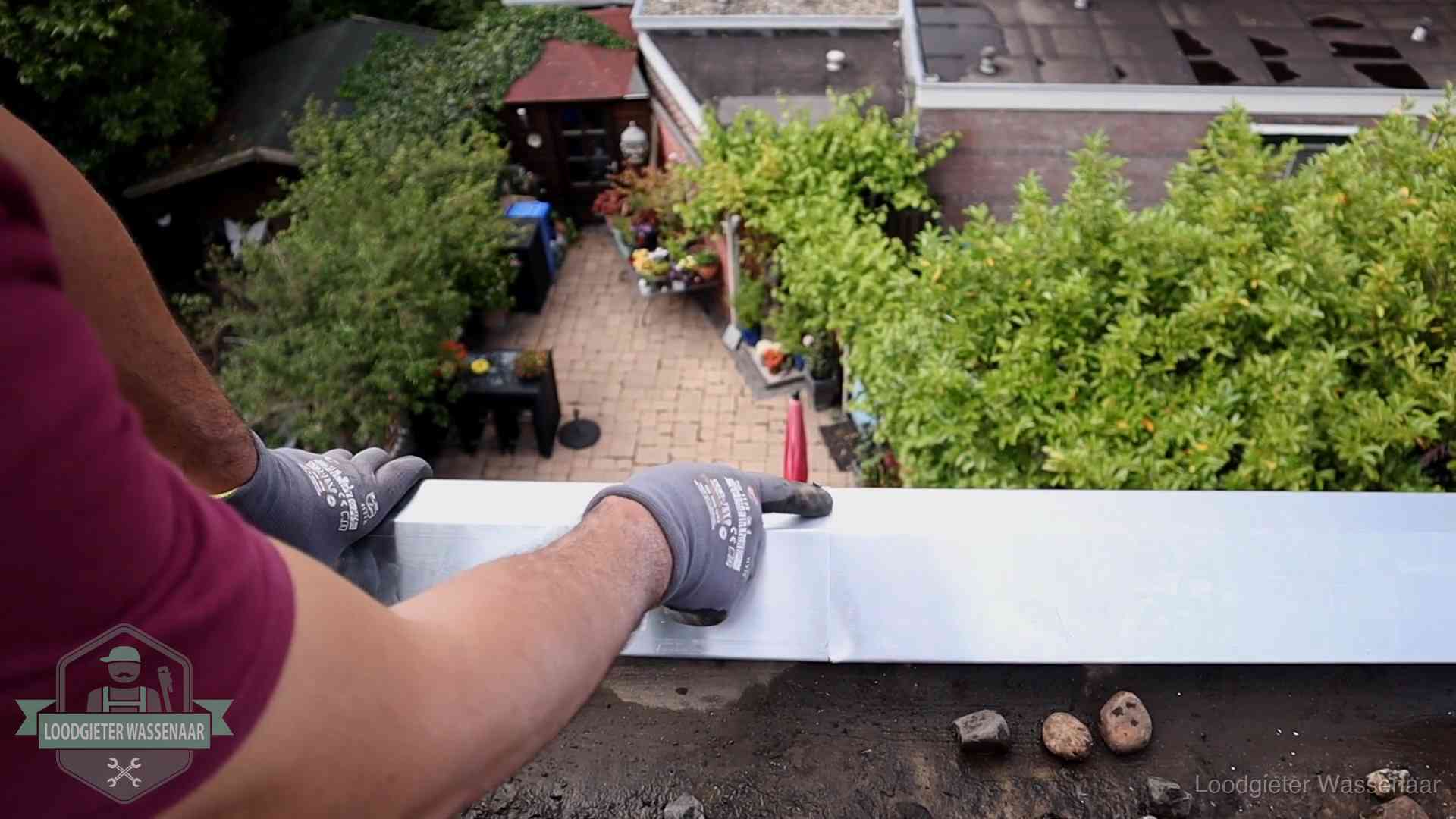 Daklekkage geregeld in Wassenaar Vakman plaatst een daktrim op de dakrand van een woning in Wassenaar