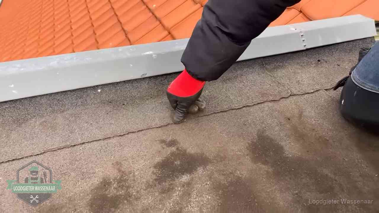 Lekkage bij de naad van een plat dak in Wassenaar Vakman wijst een naad met vochtplekken aan op een bitumen plat dak in Wassenaar
