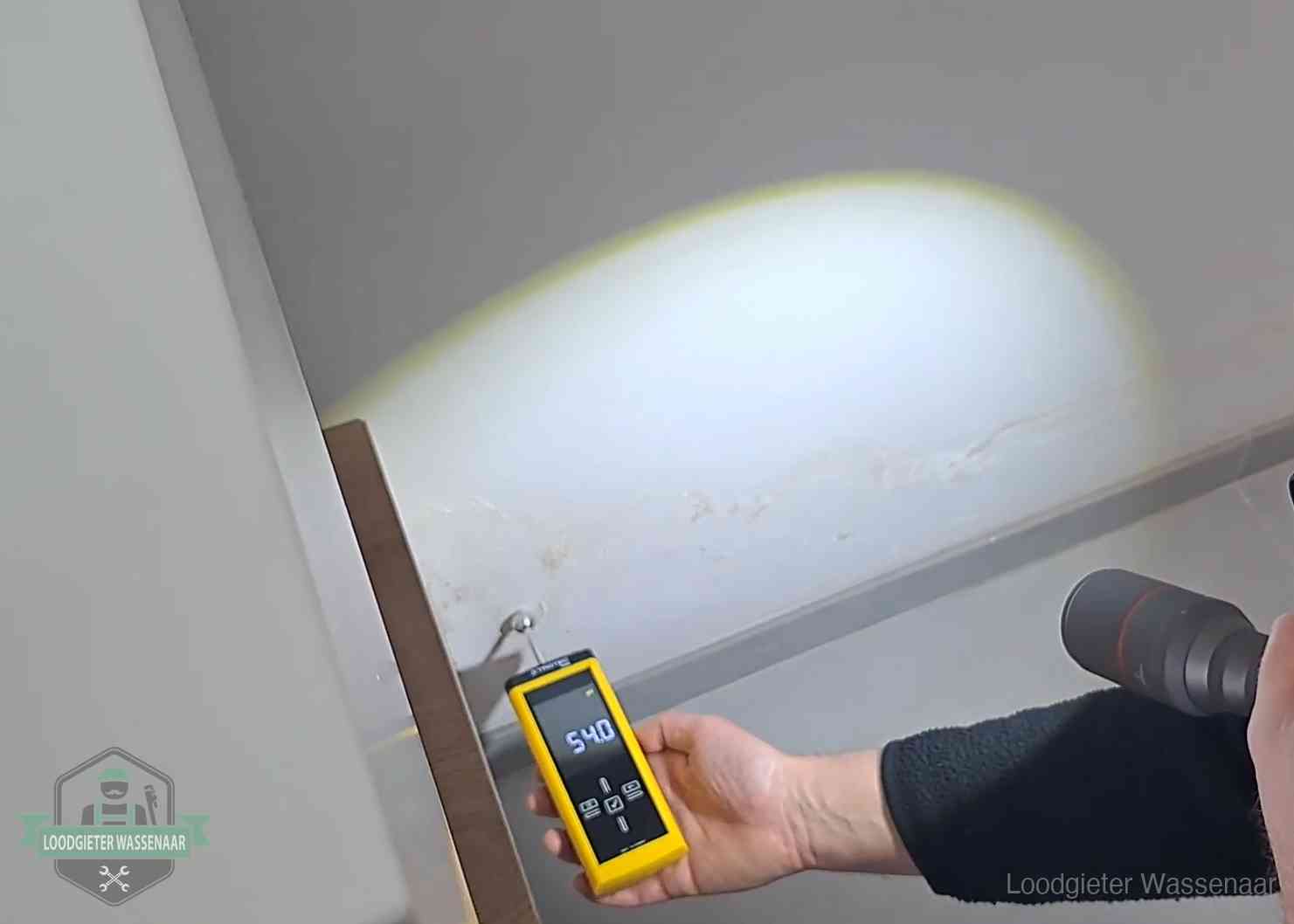 Vochtmeter tegen een natte wand met lekkagesporen in Wassenaar