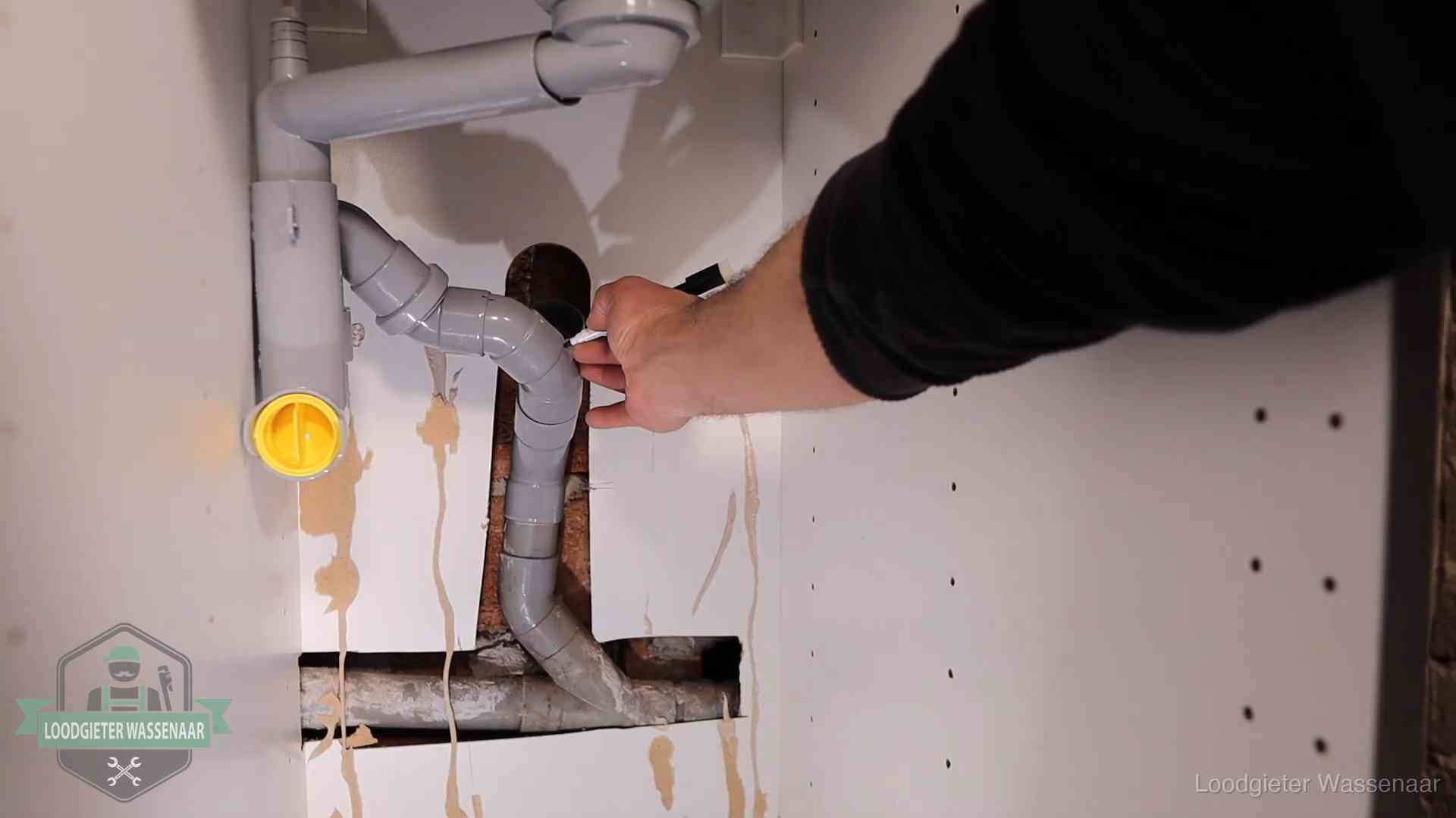 Loodgieter voor verhuurders en bedrijven in Wassenaar Loodgieter markeert een pvc-afvoerbuis onder een gootsteen in Wassenaar
