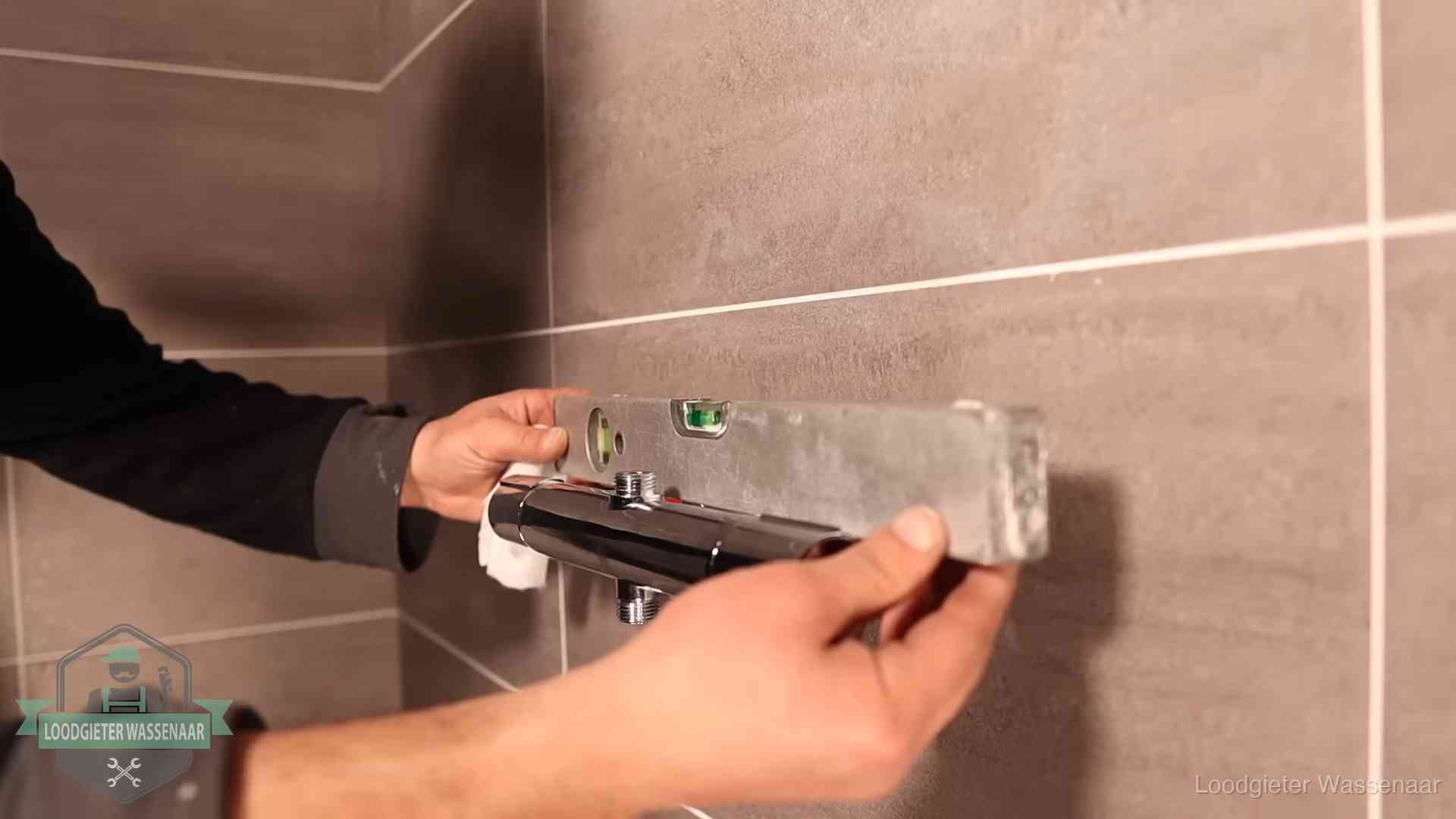 Loodgietersbedrijf voor sanitair in Wassenaar Loodgieter lijnt een douchekraan uit met een waterpas in een woning in Wassenaar