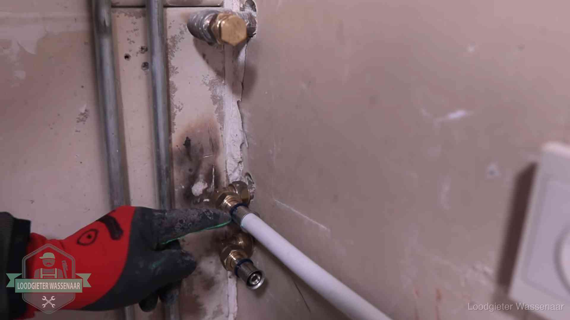 Garantie op loodgieterswerk in Wassenaar Loodgieter wijst de persfitting op nieuwe muuraansluitingen aan in een woning in Wassenaar