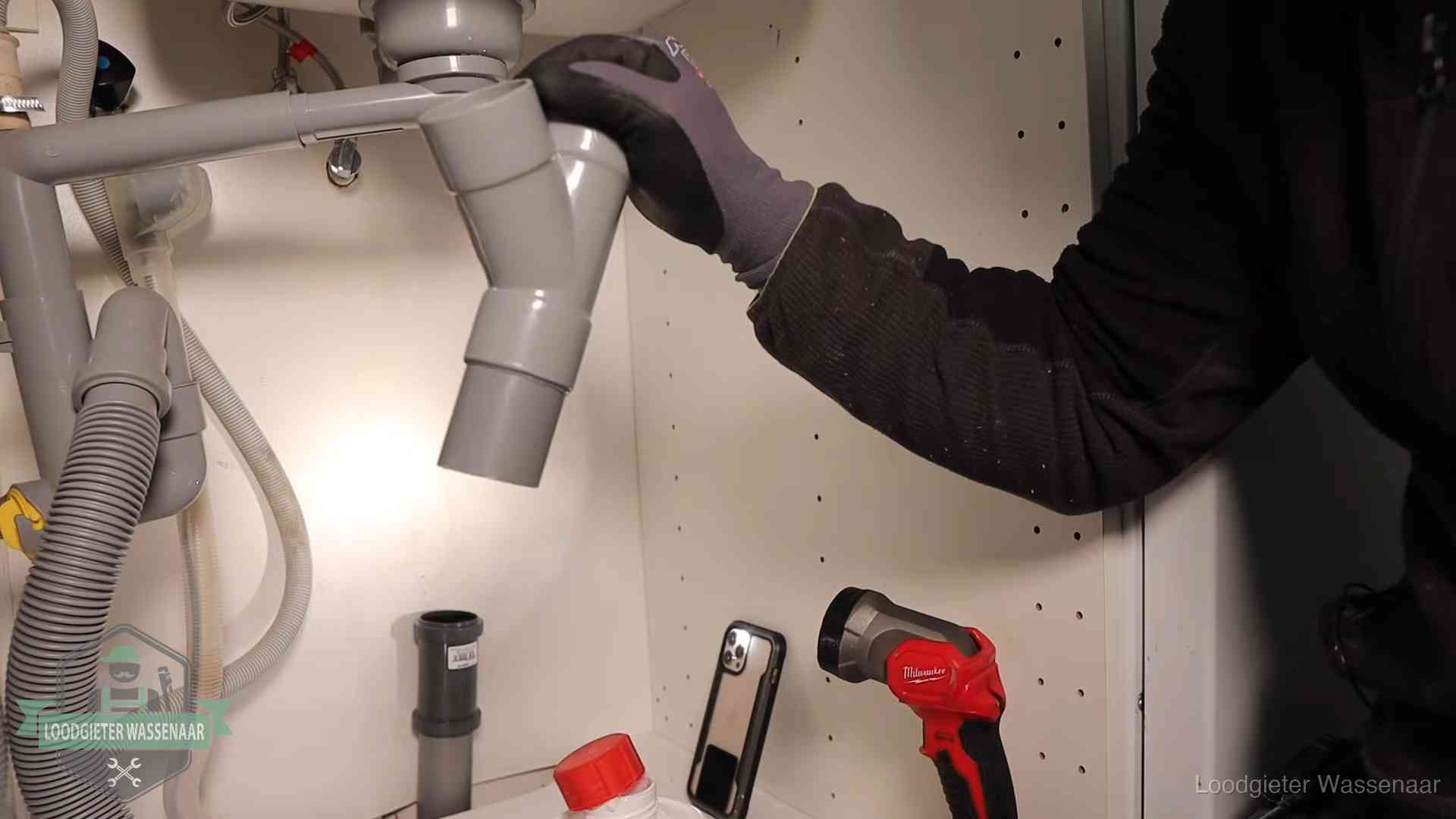 Loodgieter demonteert het sifon- en afvoerwerk onder een gootsteen in Wassenaar bij stankklachten