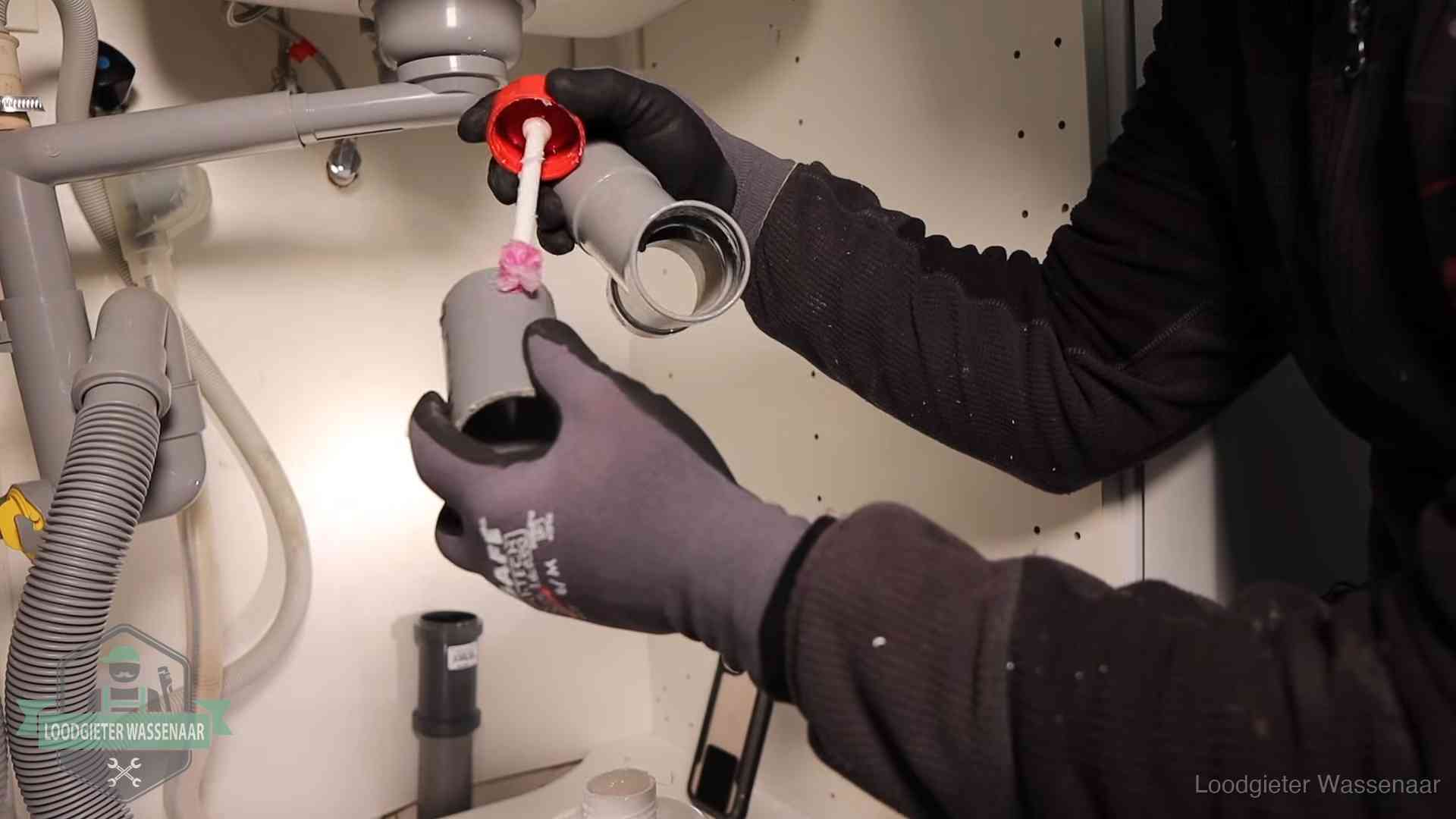 Loodgieter demonteert en reinigt de sifon onder een keukenkast in Wassenaar