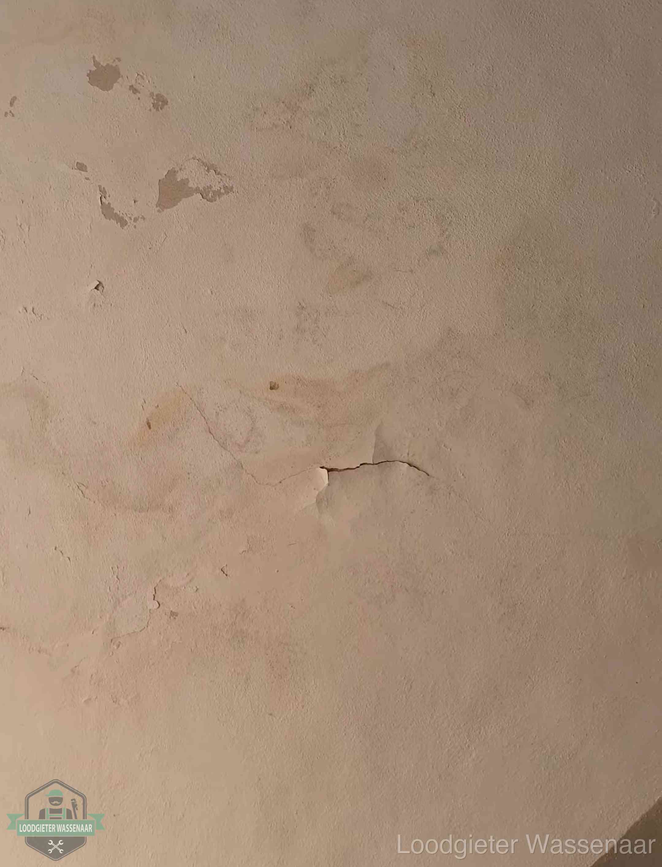 Vochtkringen en afbladderende verf op een plafond in Wassenaar, schade voor het meetrapport en de verzekering