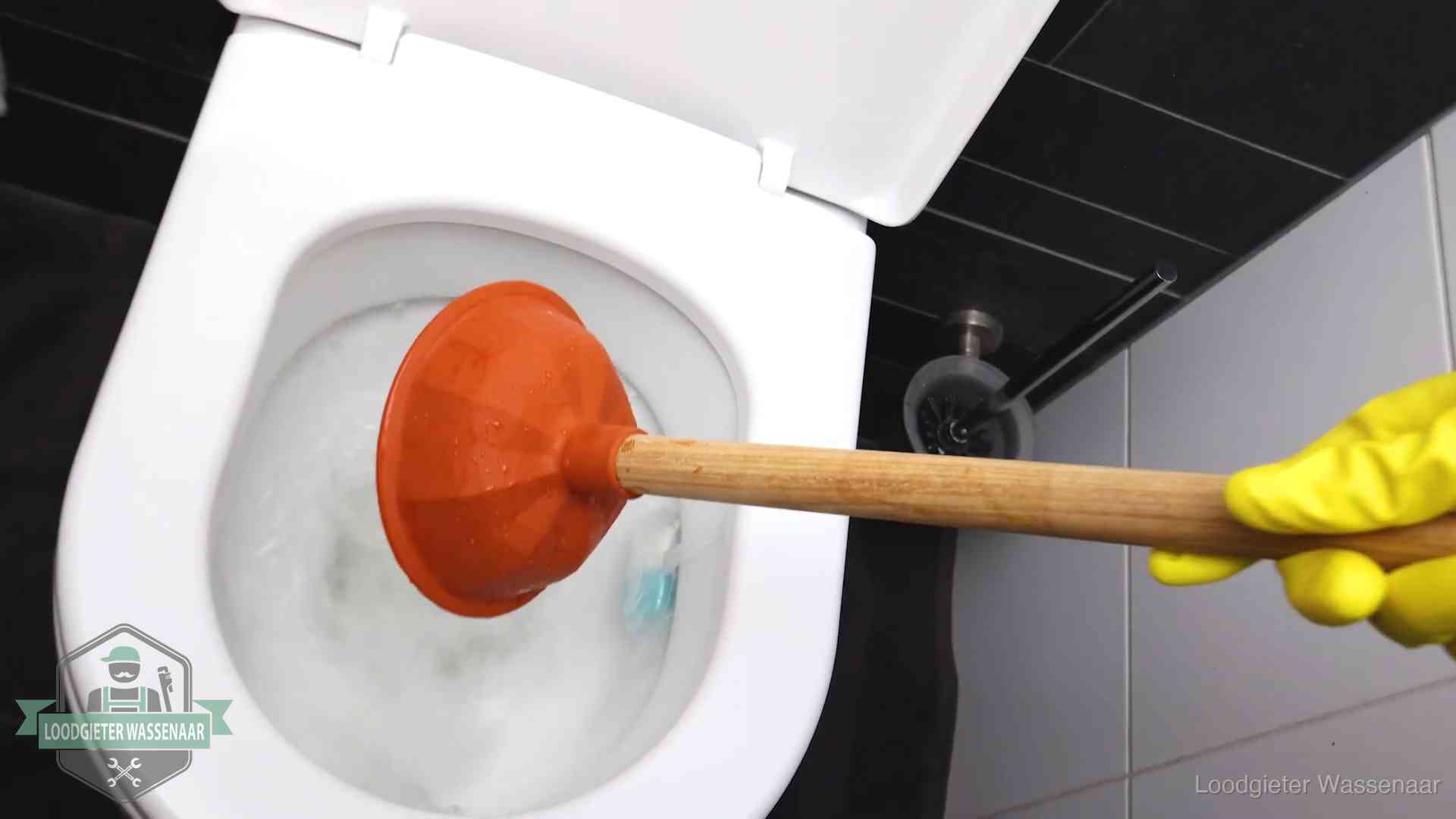 Plopper wordt in de wc-pot gedrukt bij het ontstoppen van een toilet in Wassenaar